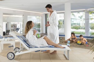 Zona de piscina interior moderna con una tumbona, una pequeña mesa con una bebida y vistas a la piscina.