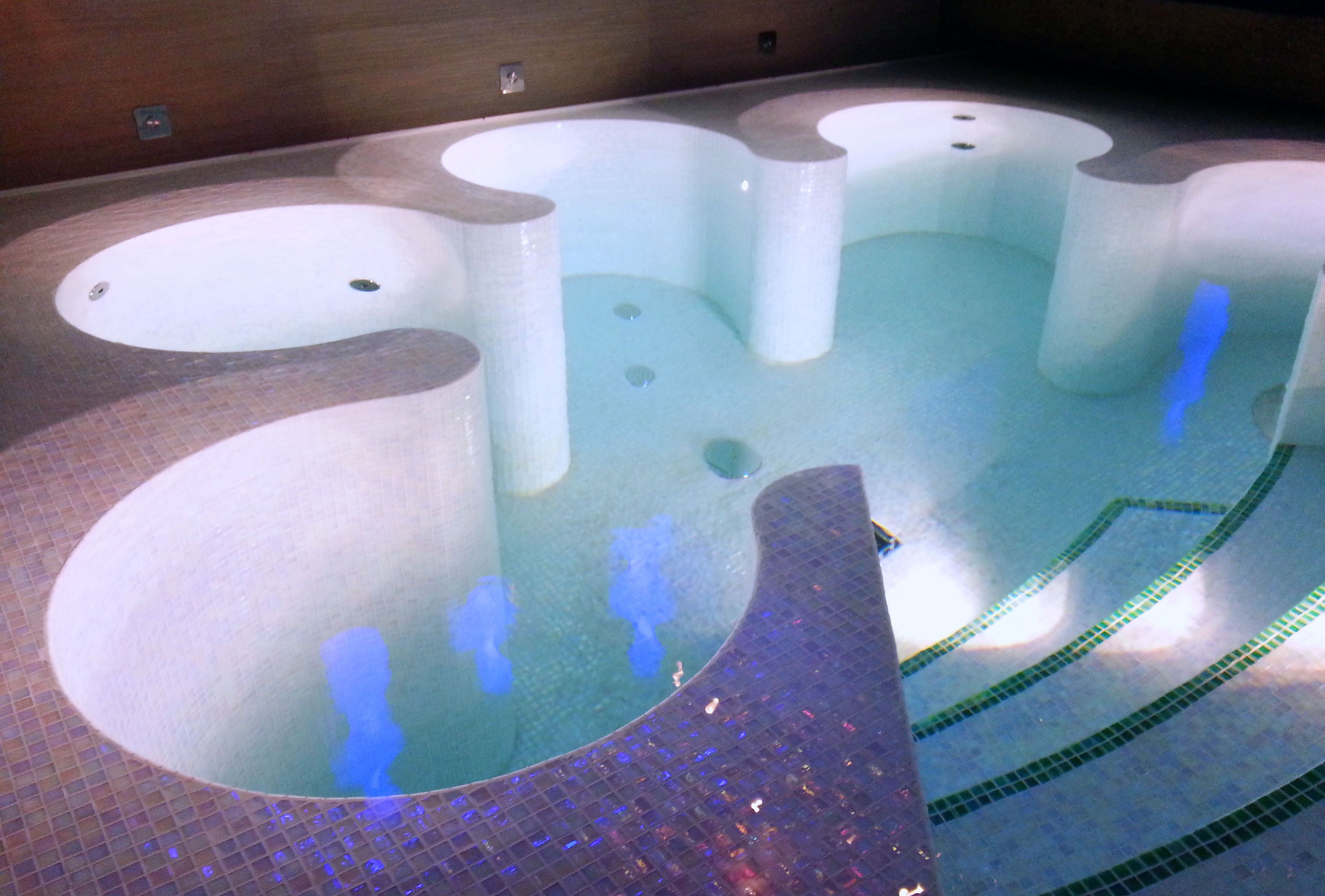 A spa pool with multiple hot tubs and a tiled floor.