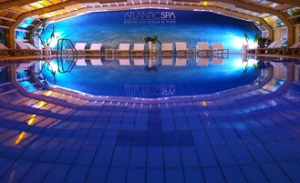 Una piscina interior con sillas de descanso y un amplio mural del océano.