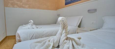A hotel room with two beds, each with a neatly folded towel.