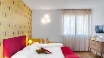 Una habitación de hotel con una cama grande, un escritorio con televisor y una ventana con cortinas.