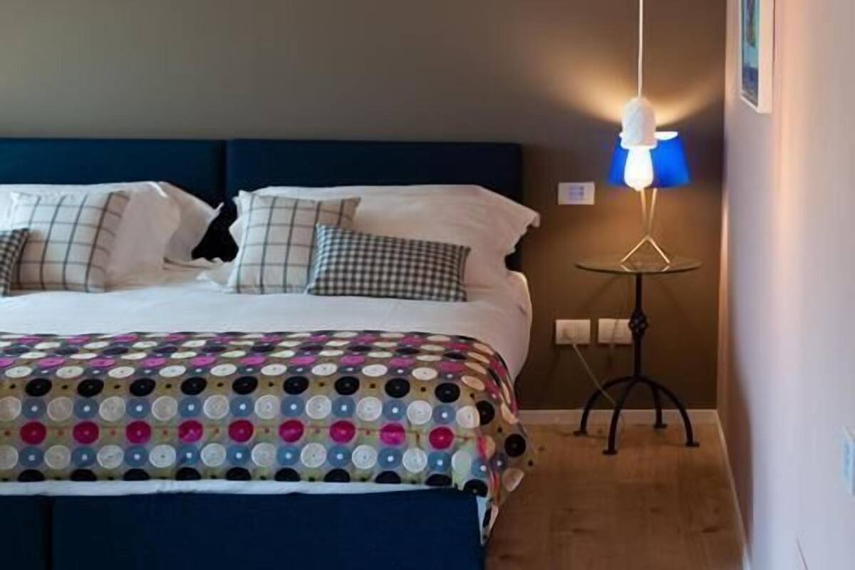 A bedroom with a bed, a bedside lamp, and hanging light fixtures.