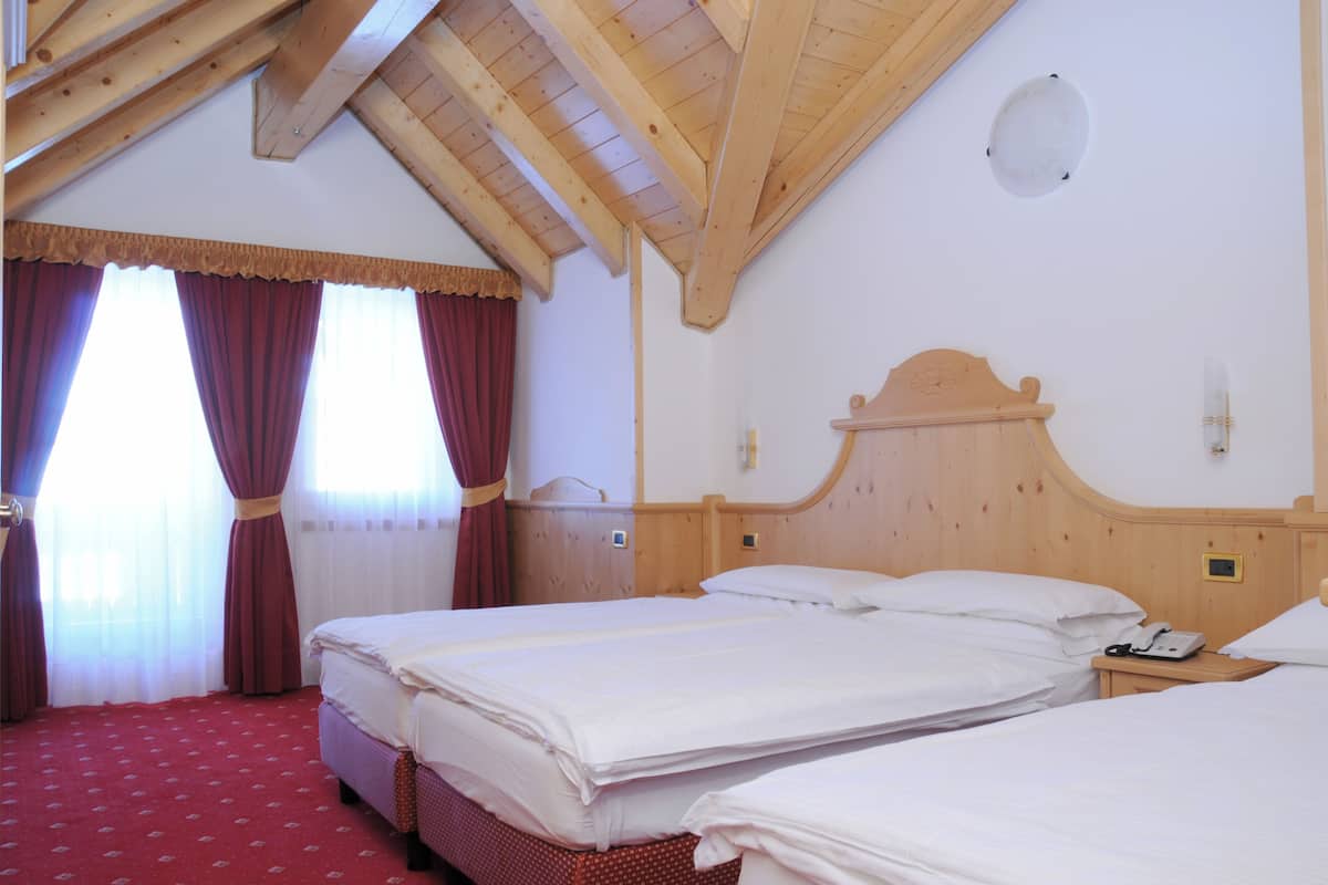 A hotel room with two beds, wooden headboards, a red carpet, and a wooden ceiling.