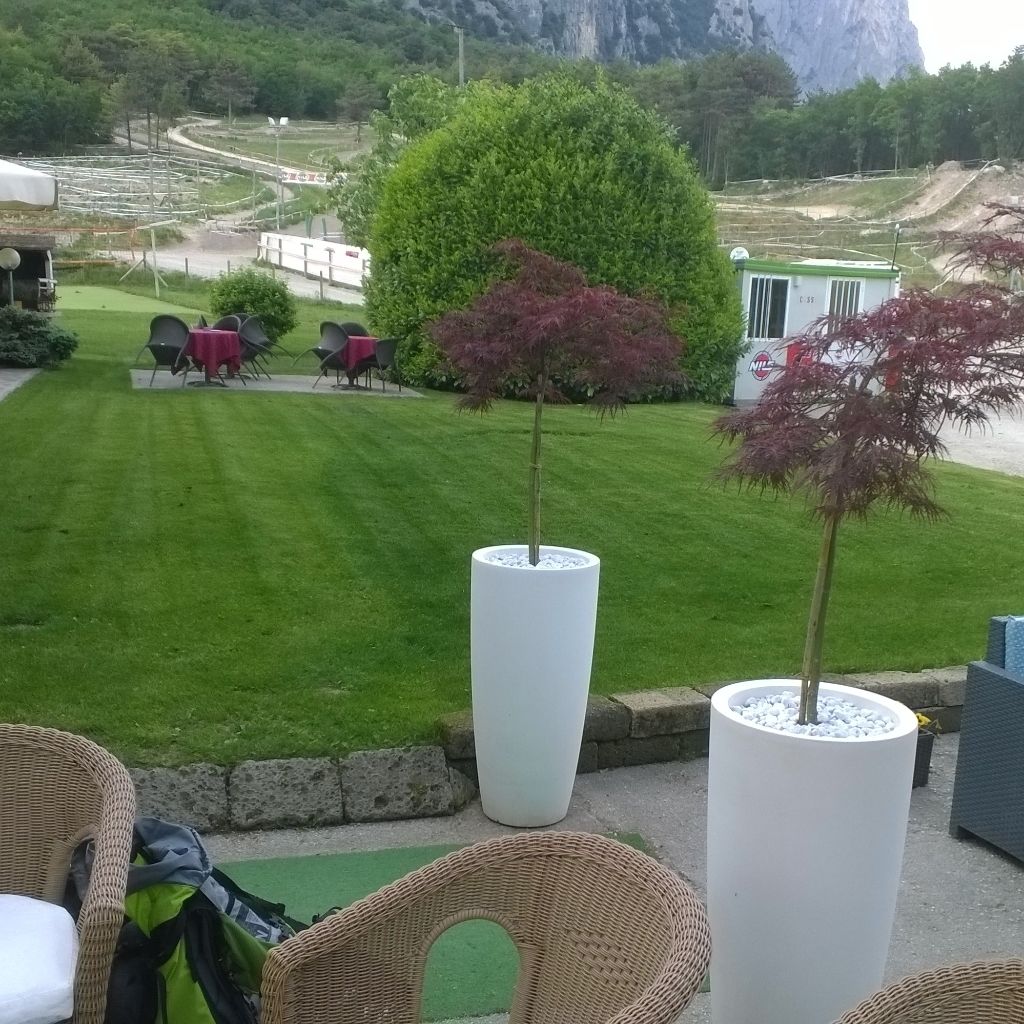 Un espacio exterior bien cuidado, con césped, algunas plantas en macetas y mobiliario de jardín.