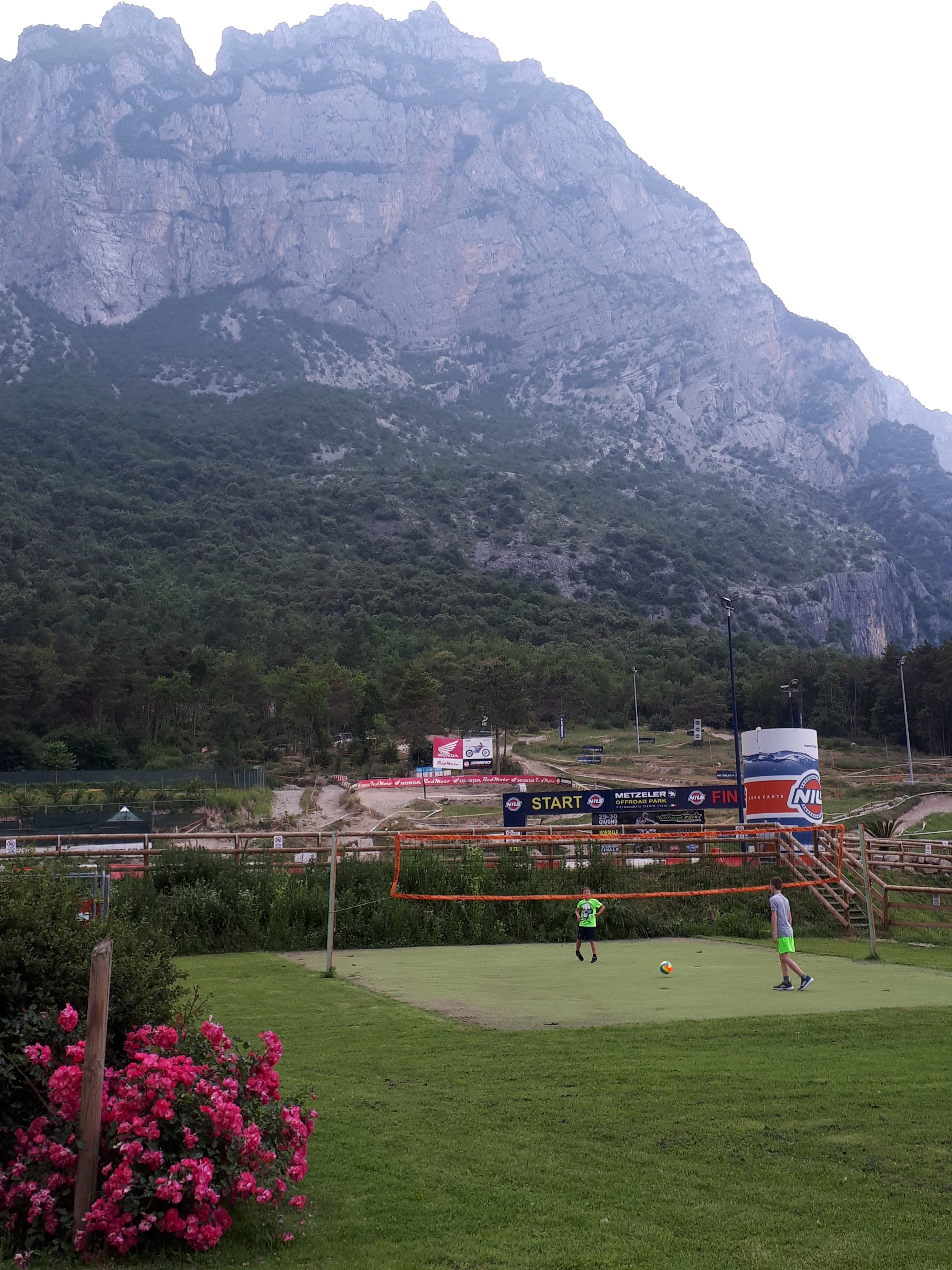 A golf course with a mountainous backdrop, a start sign, and a visible path leading to the tee area.
