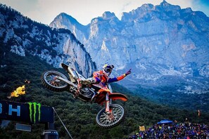 Un motociclista realiza un salto con montañas al fondo.