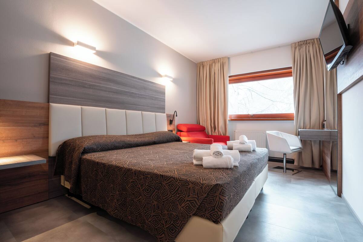 A modern hotel room with a large bed, a desk, and a chair.