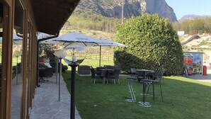 Un patio al aire libre con suelo de piedra, mesas y sombrillas.