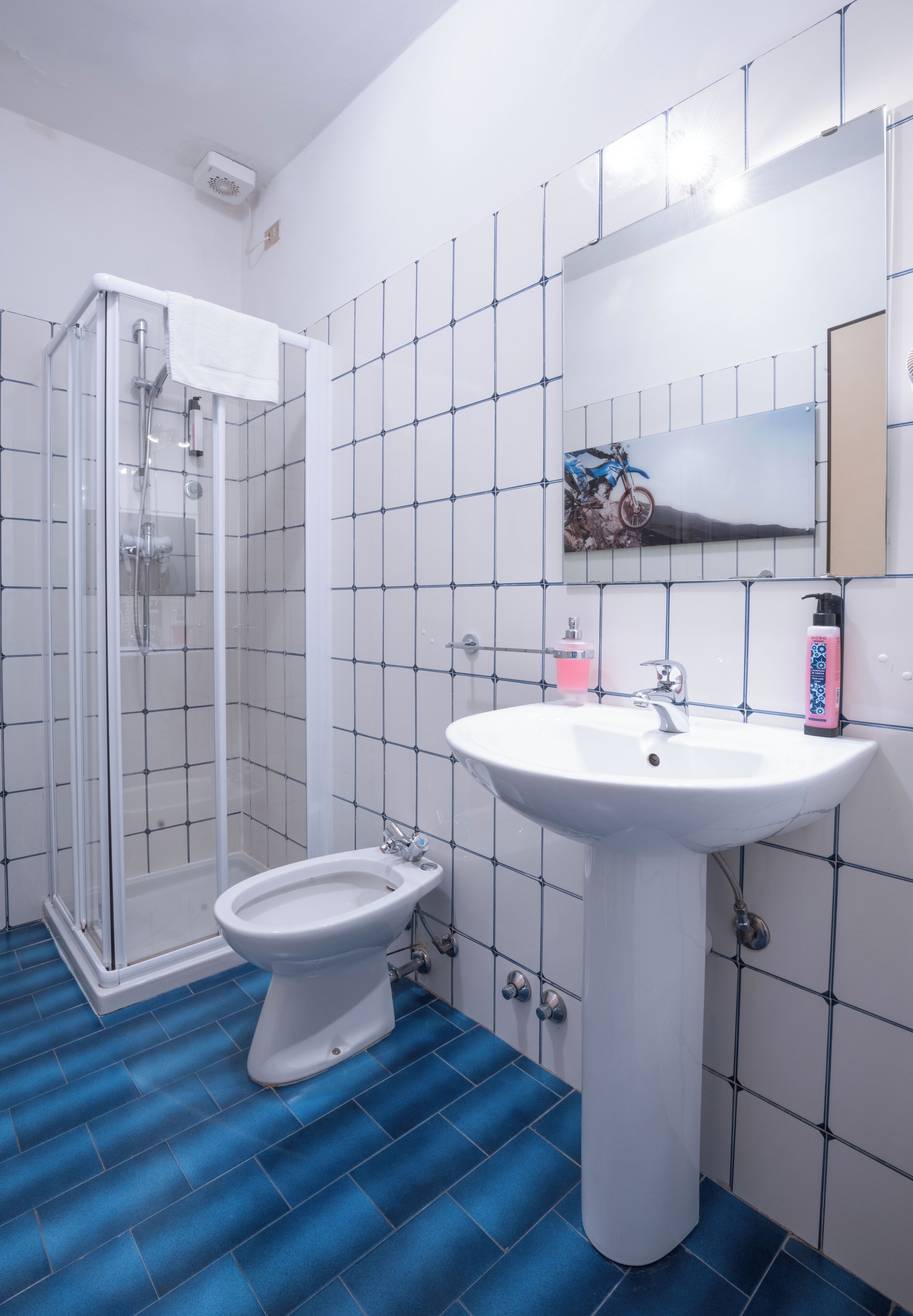 A bathroom with a glass shower enclosure, a pedestal sink, and a toilet.