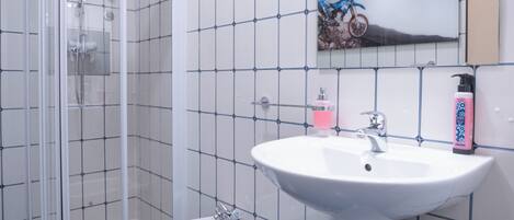 A bathroom with a glass shower enclosure, a pedestal sink, and a toilet.