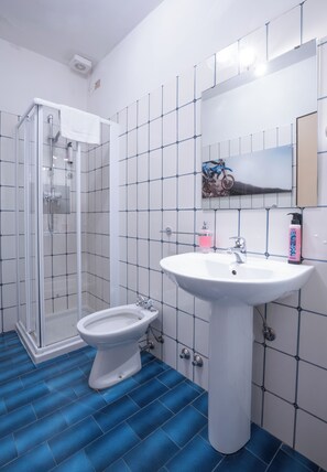 Un baño con cabina de ducha de vidrio, lavabo pedestal y retrete.