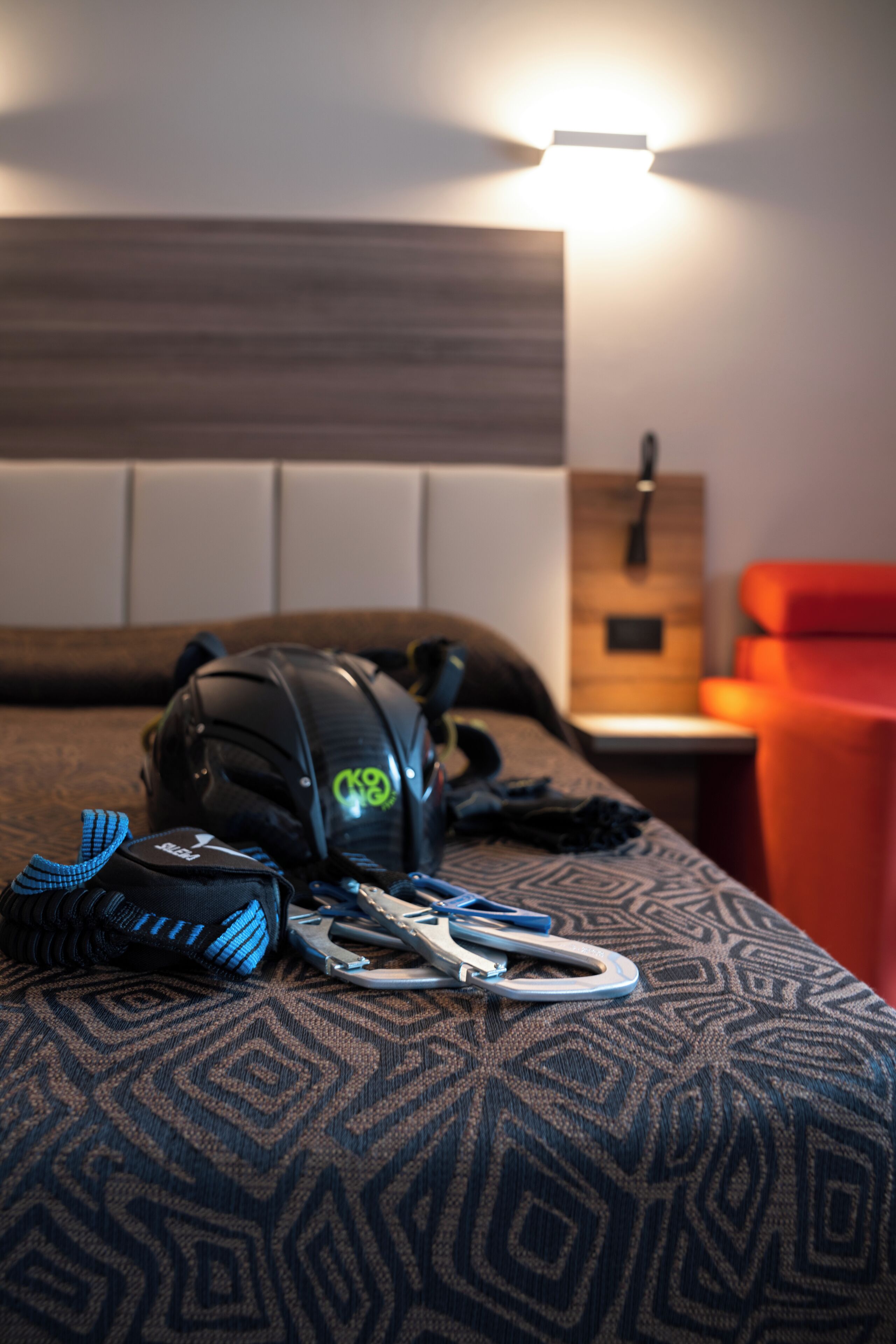 A bed with a patterned bedspread, a black backpack, and a pair of scissors on it.
