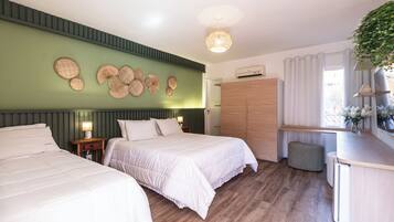Une chambre d’hôtel avec deux lits, une armoire, une table de chevet avec une lampe, un luminaire suspendu et une fenêtre avec des rideaux.