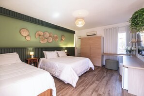 Habitación de hotel con dos camas, un armario, una mesita de noche con lámpara, una lámpara colgante y una ventana con cortinas.