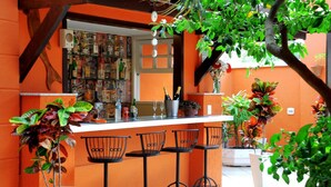 A bar area with a counter, bar stools, and a variety of bottles and glasses. - Pousada El Parador (Búzios)