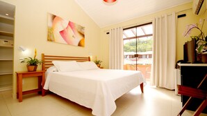 A neatly arranged bedroom with a bed, bedside tables, a desk, and a window with curtains. - Pousada El Parador (Búzios)