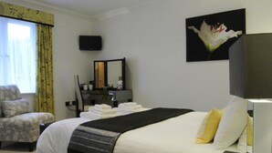 A hotel room with a bed, a chair, a desk, a mirror, and a painting. - The Old Dairy Farm (Emsworth)