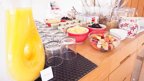 A buffet table with various food items, including bowls of fruits, cereals, and a large pitcher of orange juice. - The Old Dairy Farm (Emsworth)