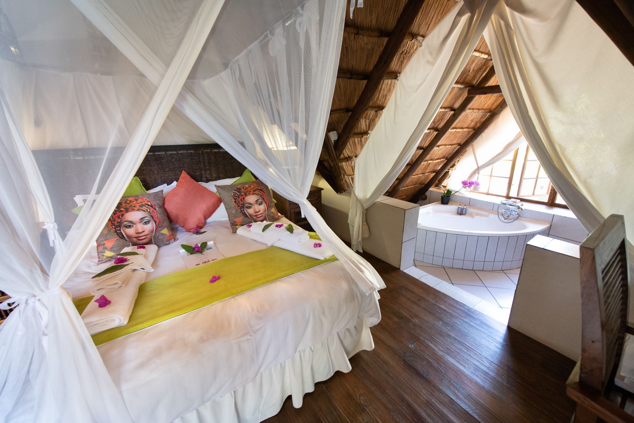 A bedroom with a canopy bed, a small bathroom, and a view of the outside.