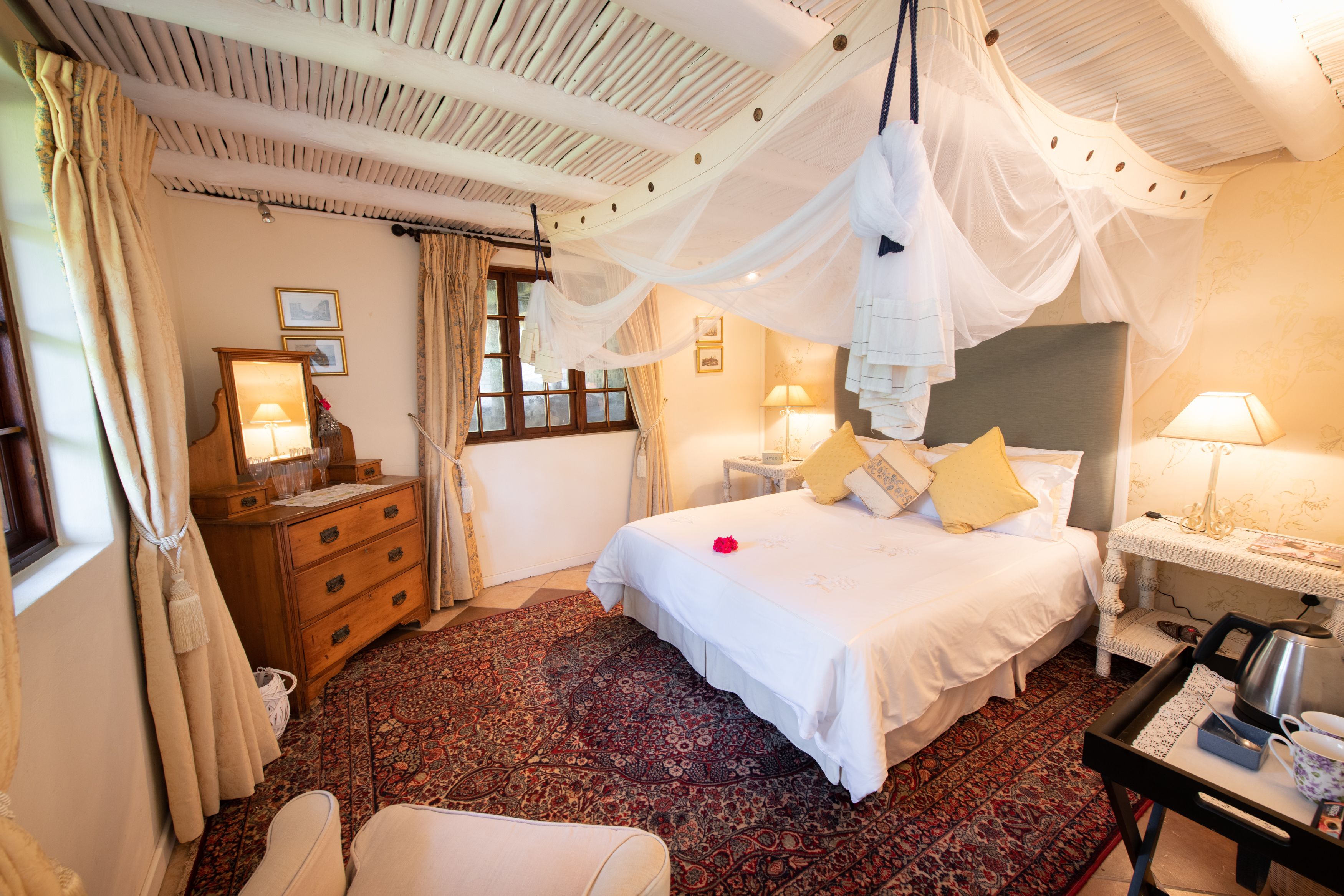 Un dormitorio con cama, mesitas de noche, cómoda, silla y dosel.