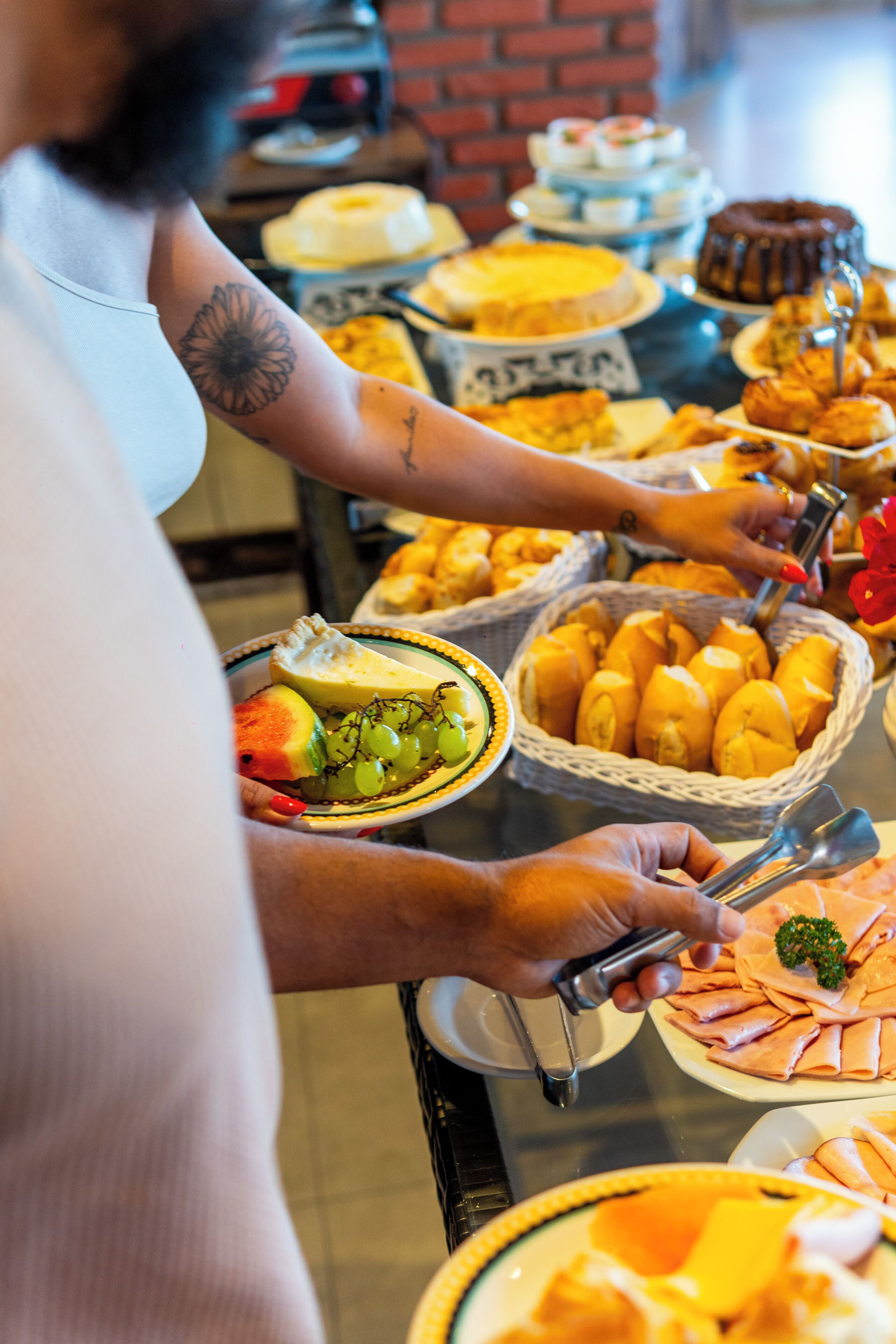 A buffet table with various food items and a person serving themselves.