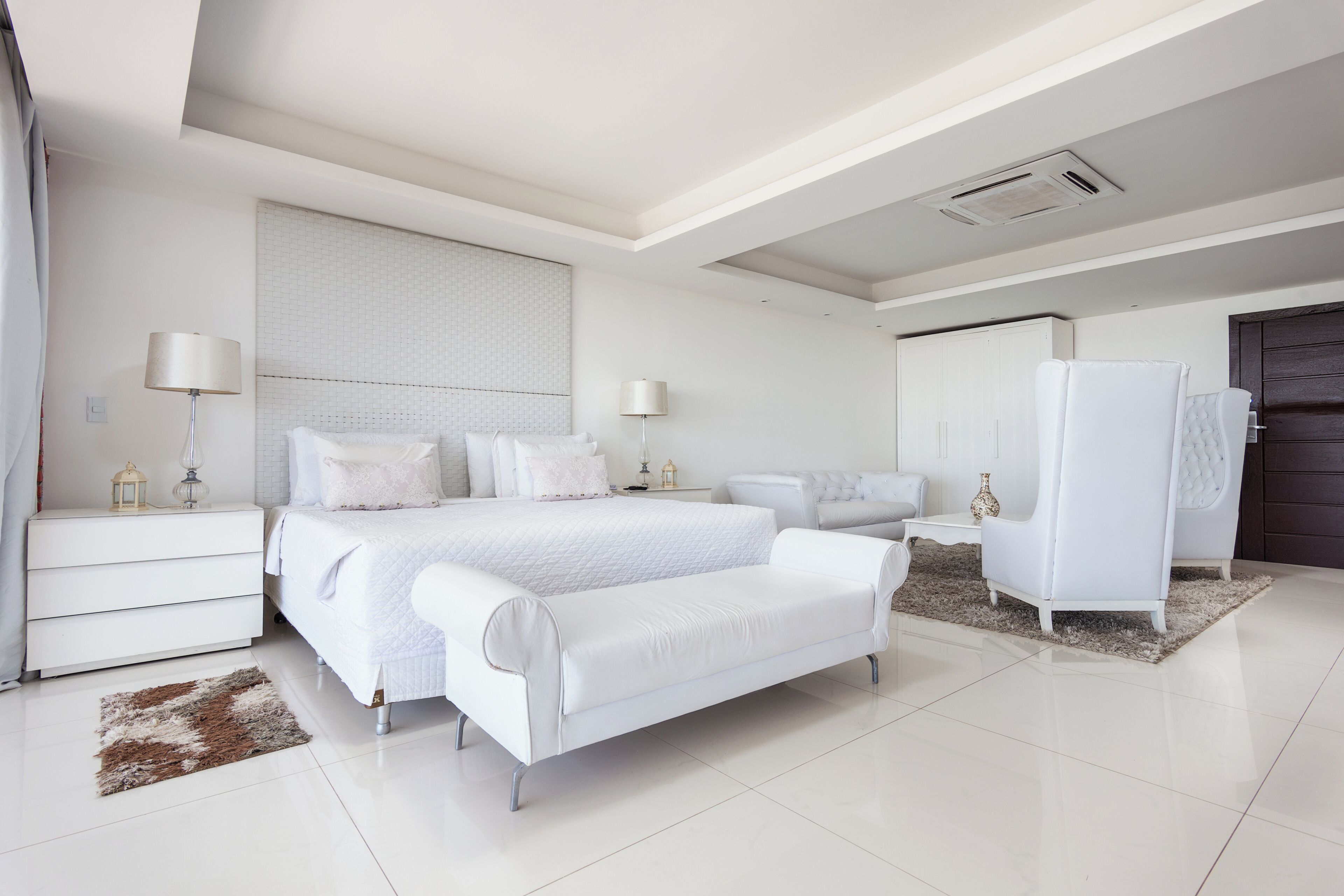 Une chambre moderne avec un grand lit, des tables de chevet, un canapé et une armoire.