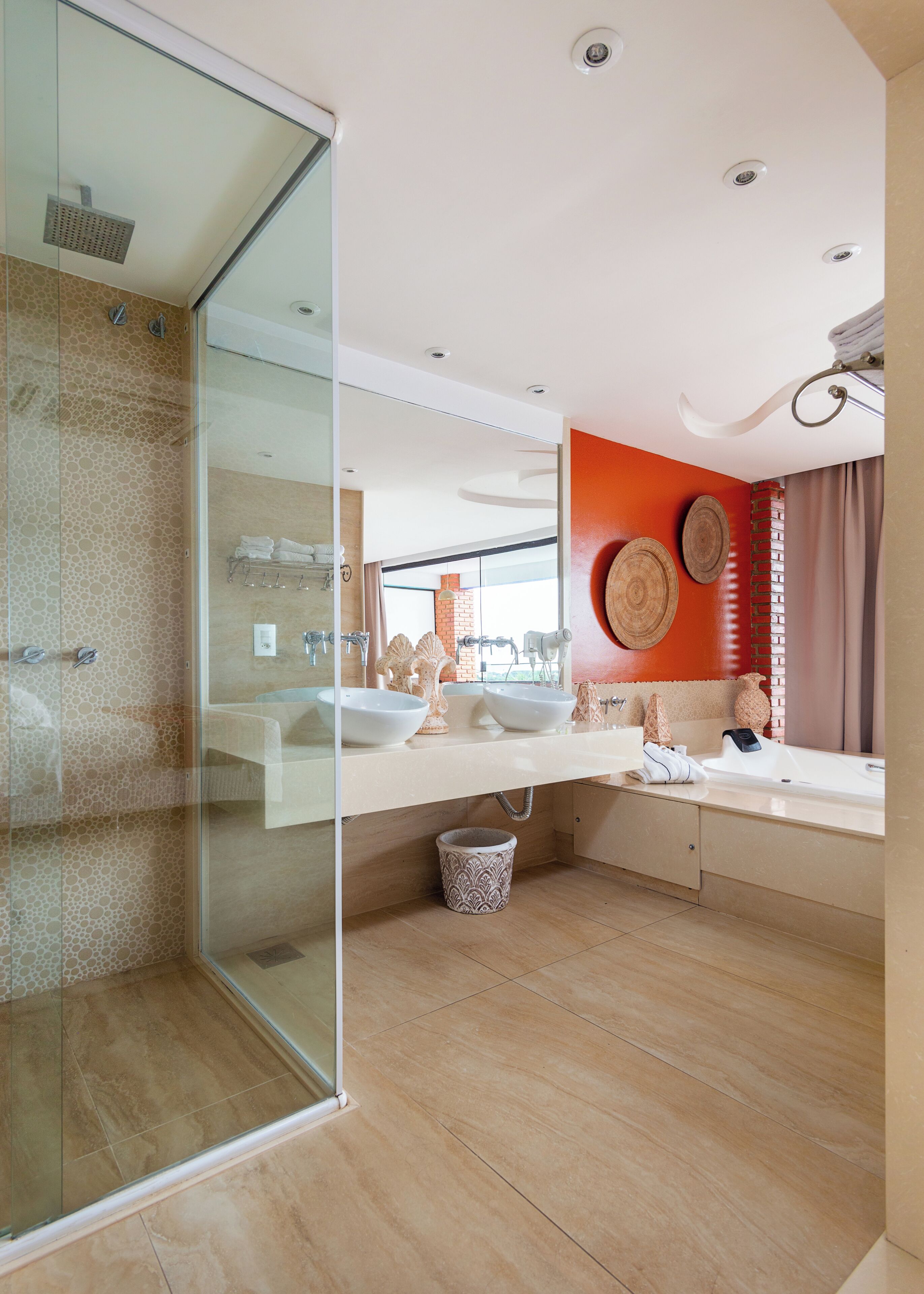A modern bathroom with a glass shower enclosure, two sinks, and a visible brick wall.