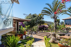 A garden with a wooden deck, potted plants, and a palm tree. - Costa do Sol Boutique Hotel (Búzios)