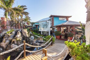 Een resort met een houten terras, een rotstuin en een gebouw met een blauw dak.