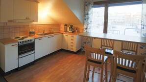 Une cuisine équipée d’une cuisinière, d’un évier et de chaises en bois.