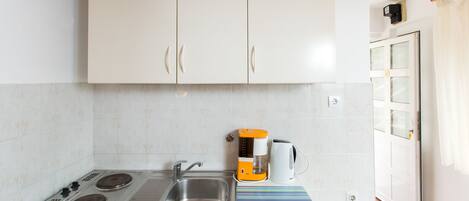 Una cucina funzionale con mobili bianchi, un fornello, un lavandino e una macchina da caffè.