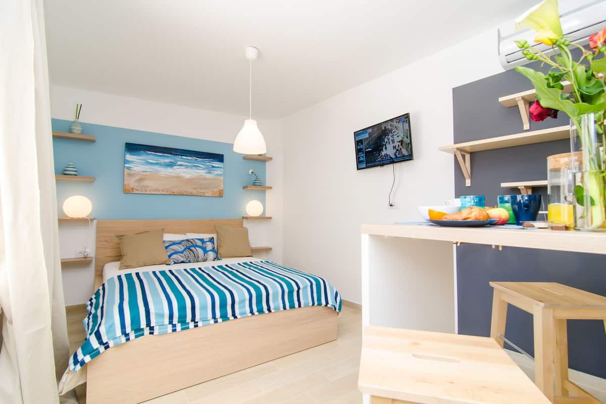 A modern bedroom with a bed, bedside tables, a TV, and a breakfast bar.