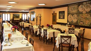 A long dining hall with multiple tables set for a meal, featuring a large wall map and framed artwork. - Des Alpes (Castione della Presolana)