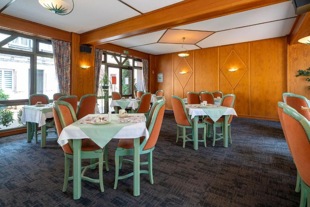 A dining area with tables and chairs, wooden walls, and windows.