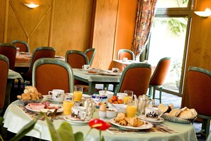A breakfast setting with tables set for dining, featuring croissants, pastries, and beverages. - A la Vignette (Saint-Hippolyte)