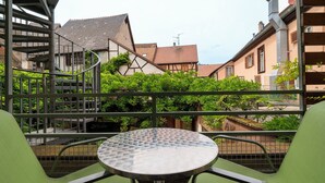 A terrace with a round table and green chairs, overlooking a garden and traditional buildings. - A la Vignette (Saint-Hippolyte)