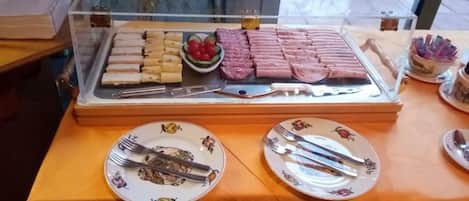 A buffet setup with various food items and utensils on plates.
