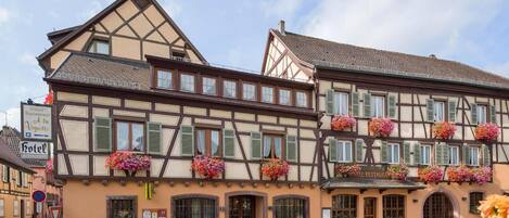 A traditional half-timbered building with multiple windows, flower boxes, and signs indicating a restaurant and hotel.