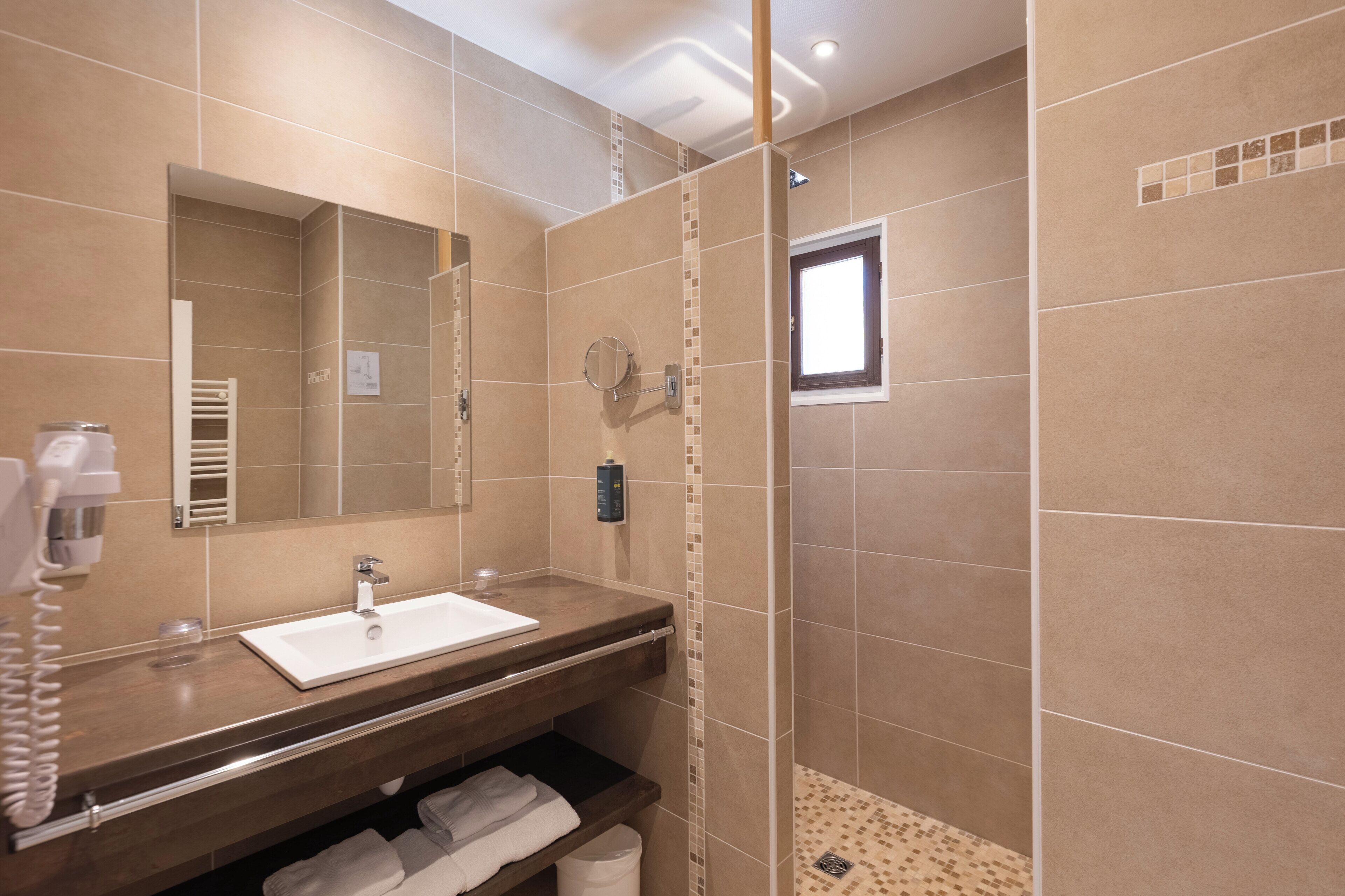 A bathroom with a sink, mirror, towel rack, and shower area.