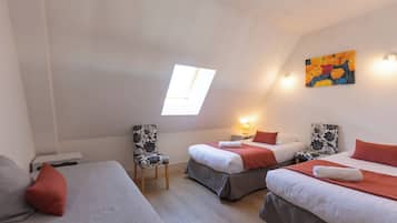 Ein Zimmer mit zwei Betten, einem Oberlicht, einem Gemälde und einem Sessel.