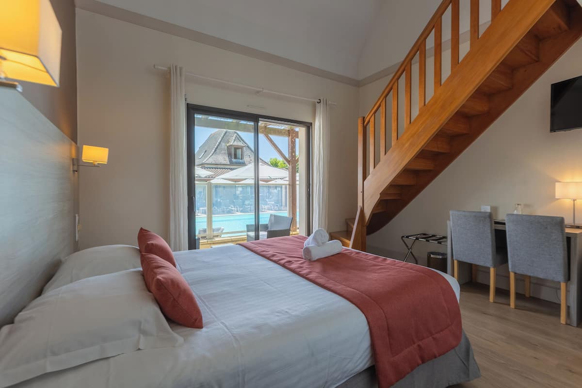 Ein Schlafzimmer mit Bett, Schreibtisch, Stuhl und Blick auf ein Gebäude.