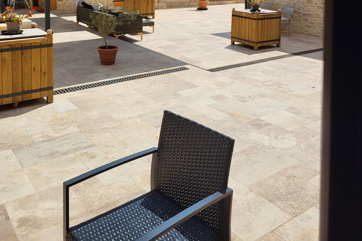 Ein Innenhof mit Steinmauern, Holzmöbeln und Pflanzen in Töpfen.