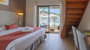 Habitación de hotel con cama, escritorio, silla y vistas a una piscina y edificios.