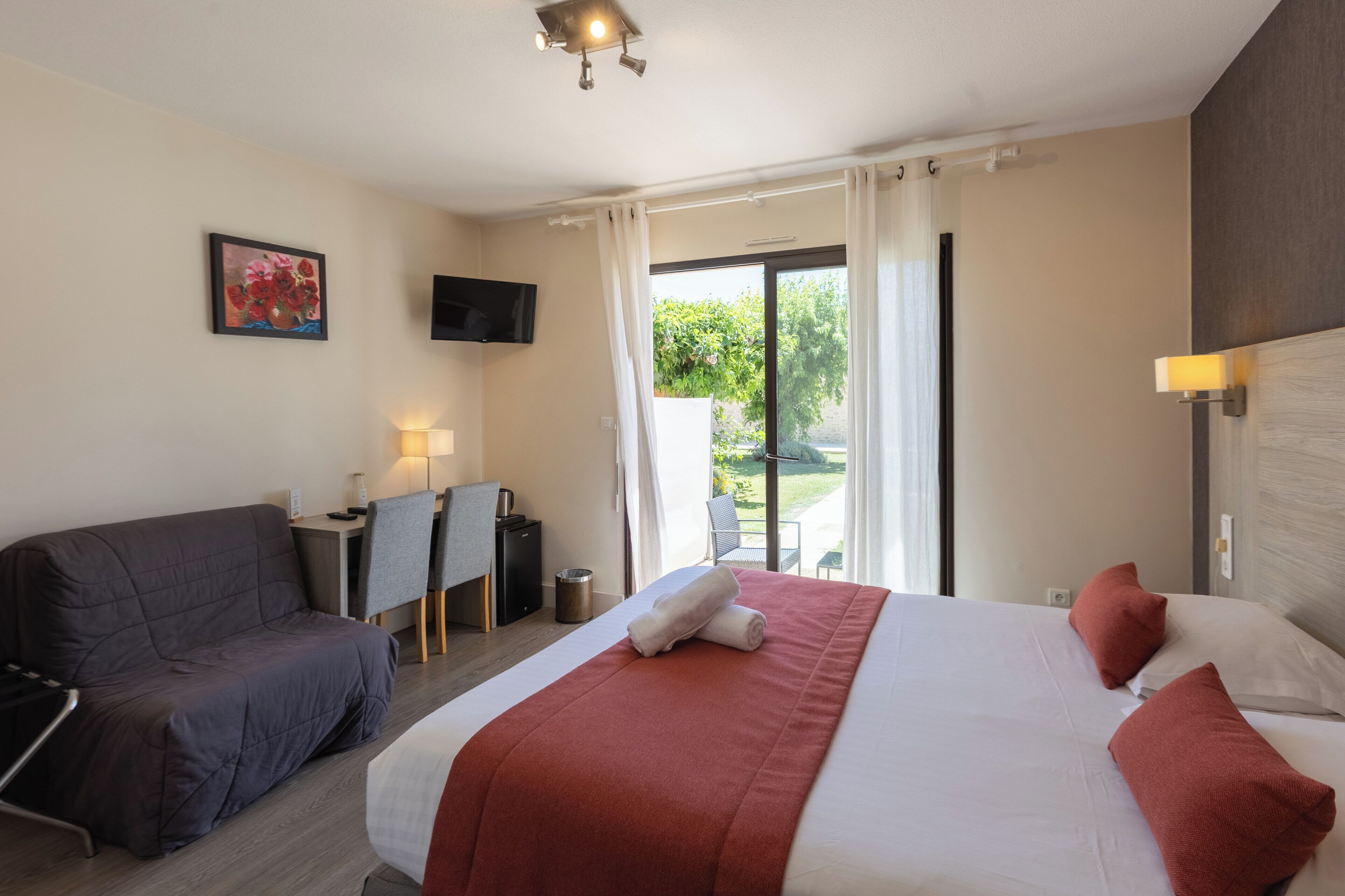 Une chambre d’hôtel équipée d’un lit, d’un bureau, d’une chaise, d’une télévision et offrant une vue sur l’extérieur.