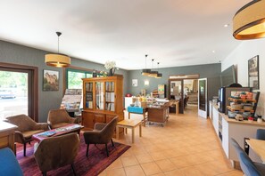 A spacious hotel lobby with a reception desk, seating area, and a large wooden cabinet with glass doors. - L'Oustal de Vézac (Vezac)
