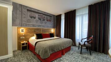 Hotelkamer met een groot bed, een houten hoofdbord, een nachtkastje, een stoel en een muurschildering.