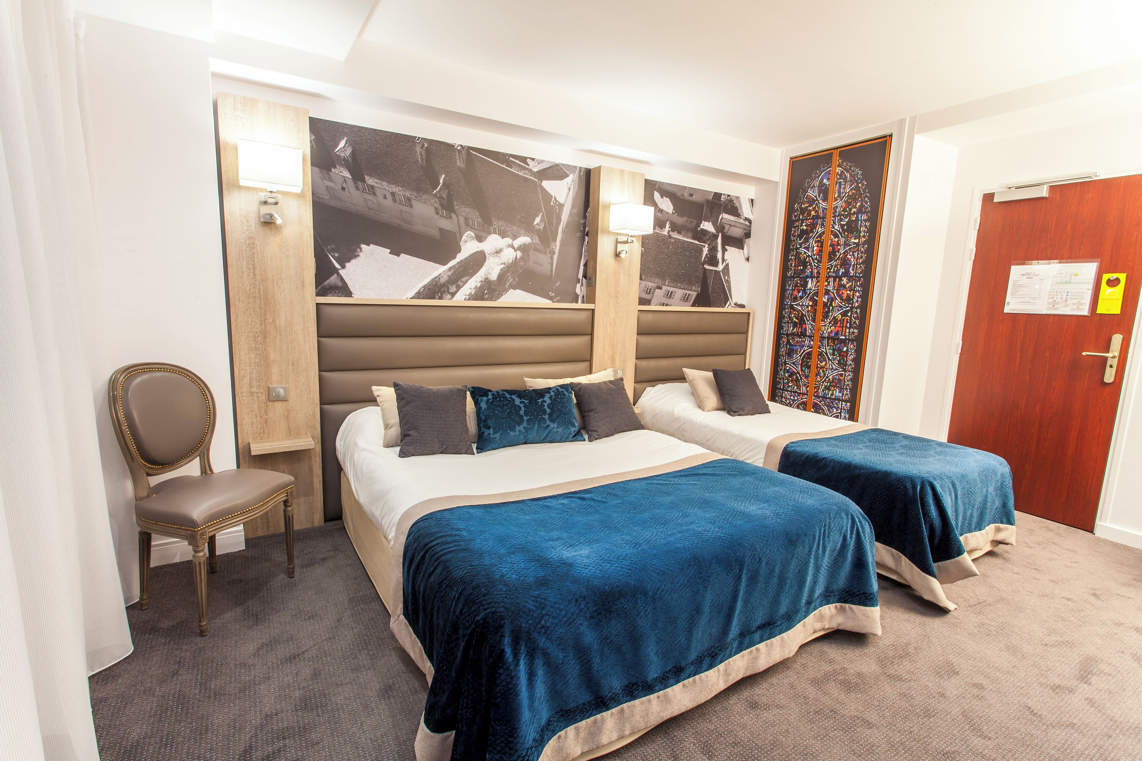 Een hotelkamer met twee bedden, een stoel en een deur met een bericht.