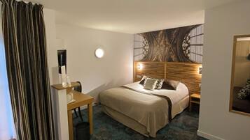 Een hotelkamer met een bed, een bureau, een stoel, een klein tafeltje, een rond tafeltje en een bank.