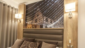 Un dormitorio con una cama grande, varios almohadones, un cabecero con luz empotrada y un tapiz decorativo sobre la cama.