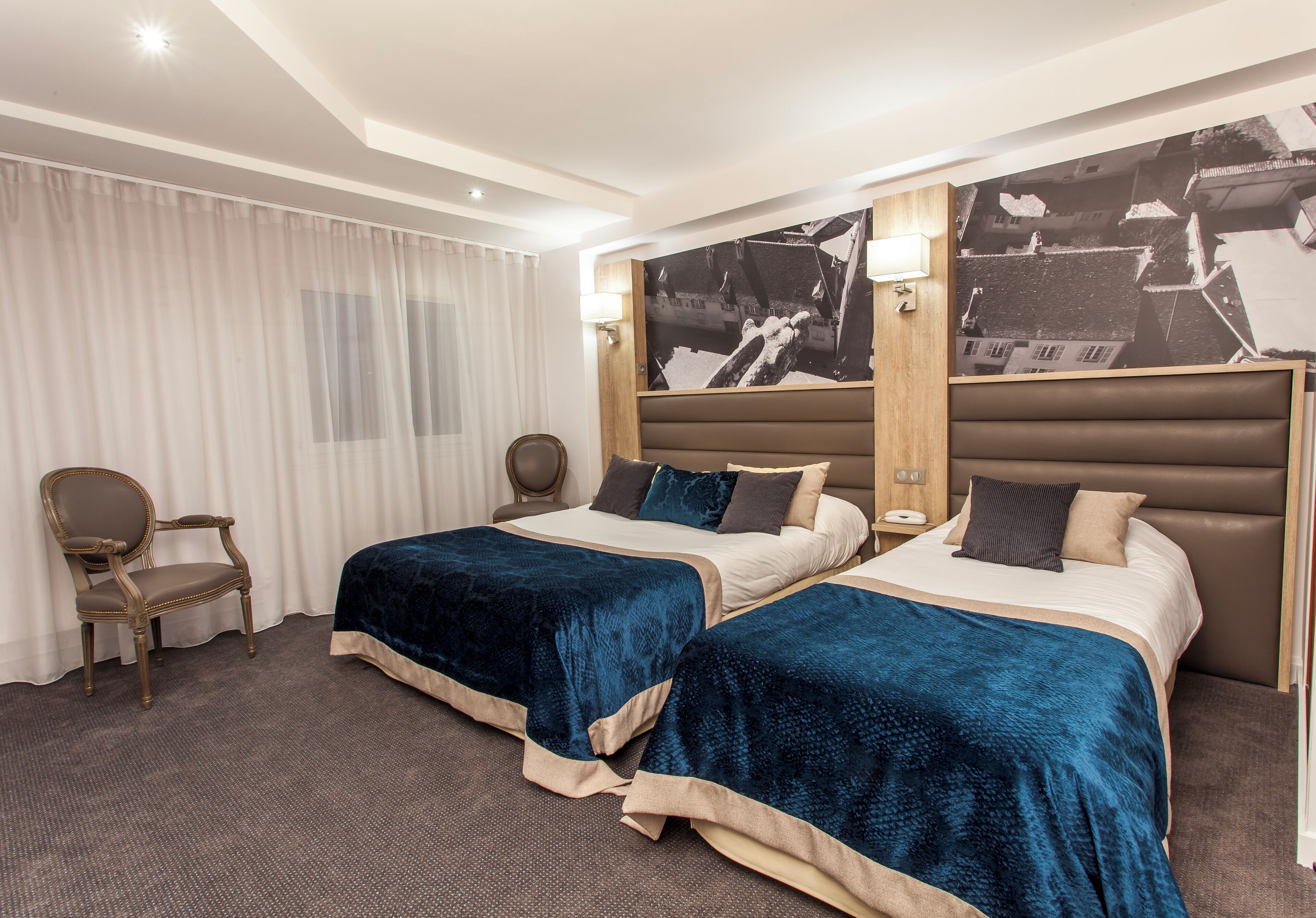 Ein Hotelzimmer mit zwei Betten, einem Sessel, einem Schreibtisch und einem großen Wandbild.